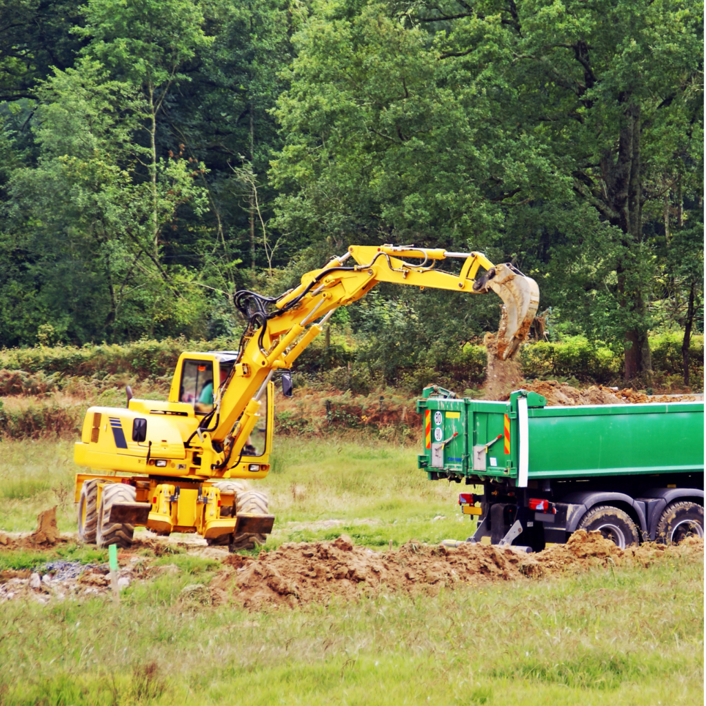 Pelle chargeant un camion benne en prairie